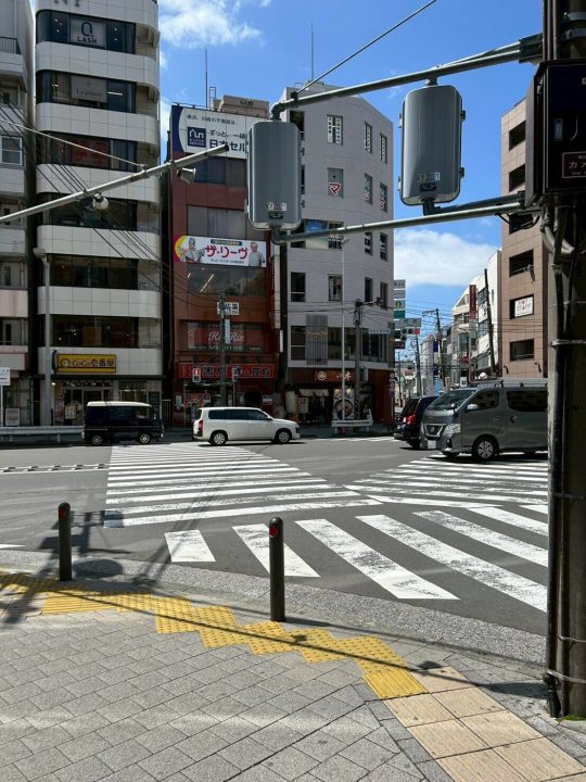 ②しばらく歩くと道路挟んで向かい側にカレーのココ壱番屋がある岡野交差点に差し掛かりますので、交差点の信号を渡りココ壱番屋の方に左折してください。